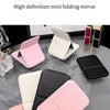A hand holds a pink folding mini mirror, showcasing its design and portability.