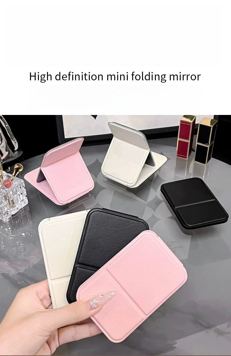 A hand holds a pink folding mini mirror, showcasing its design and portability.