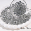A clear glass spacer bead is shown in a small glass container with many beads spilled around it.