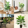 A large artificial areca palm tree in a potted plant displayed on a wooden table and next to a white shelf.