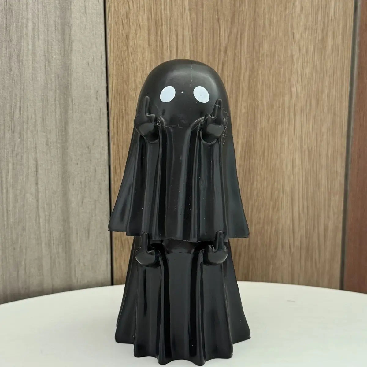 A black ghost figurine with white eyes and draped fabric, used for Halloween decor.