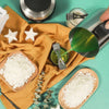 A complete candle making kit showing a melting pot, pouring pitcher, and white wax ingredients on a yellow cloth.