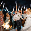 A group of people are holding LED fiber optic glow wands in a performance or celebratory setting.