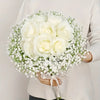 A bouquet of white roses and baby's breath flowers held by a person.