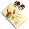 A kraft paper gift box tied with twine, decorated with red berries and pine cones.