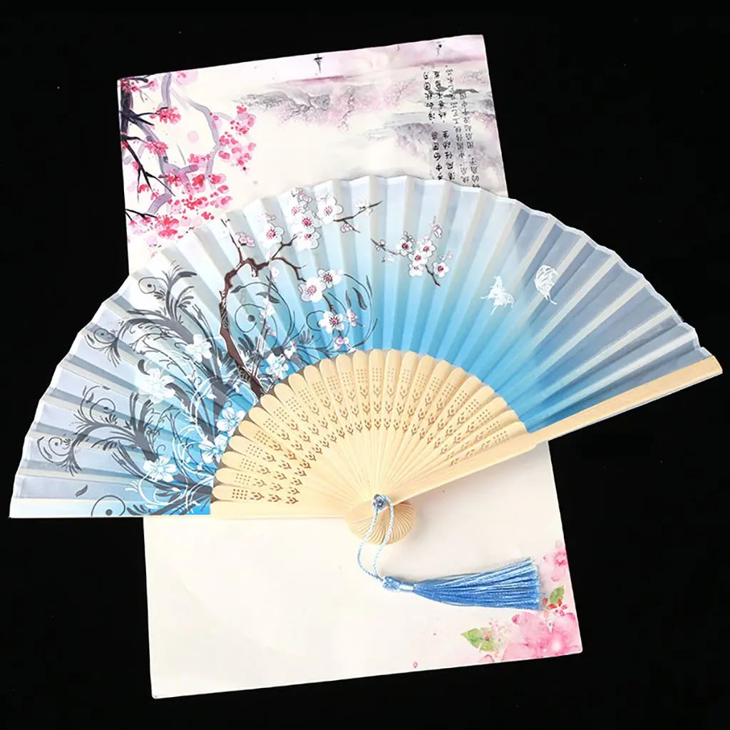 A vintage silk folding fan featuring delicate pink and blue floral patterns on a light background.