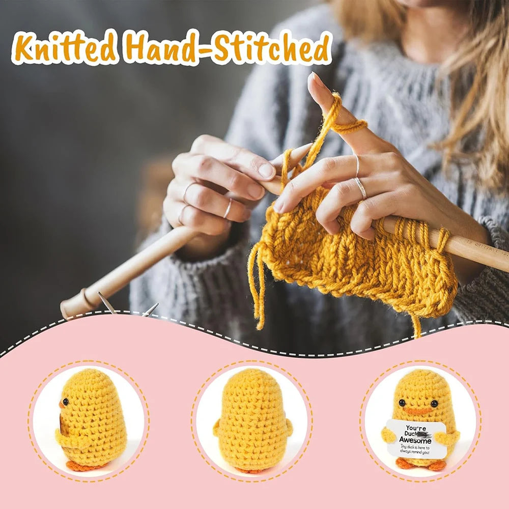 A hand knitting a yellow knitted duck plush toy with an inspirational card.