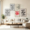 A living room wall decorated with framed vintage newspaper art featuring headlines like What If It All Works Out.