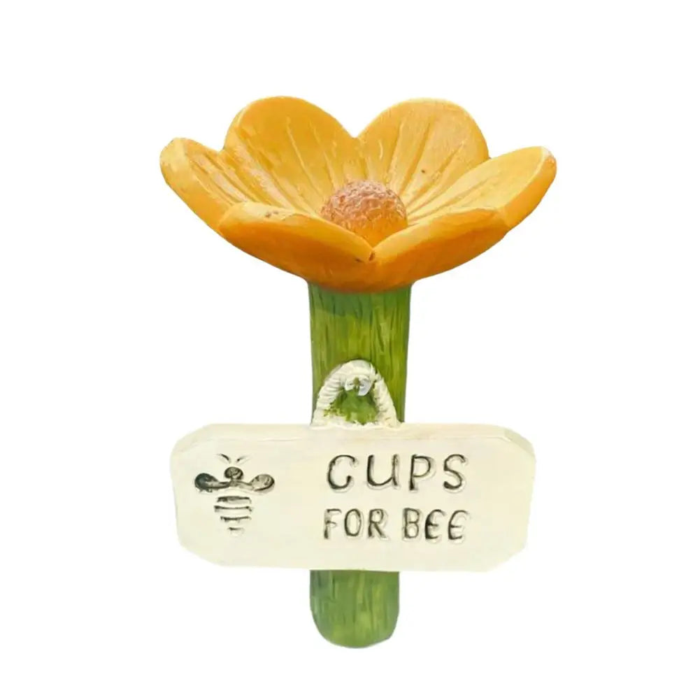 A decorative watering station featuring a bee-shaped flower and a tag that reads Gups for Bee.