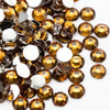 A pile of round, flatback resin rhinestones in amber and gold tones.
