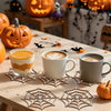 Wooden spider web ornaments displayed on a wooden table with pumpkins and coffee cups.