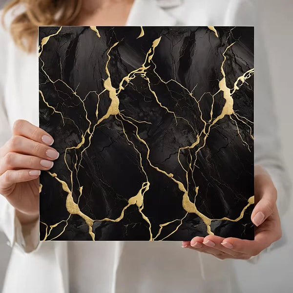 A hand holds a black marble pattern wall sticker featuring gold veining for home decor.