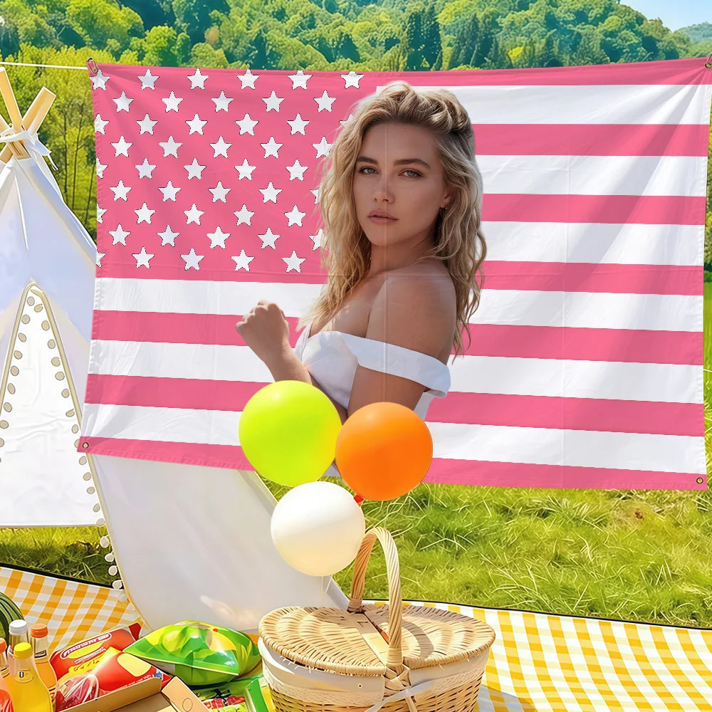 A woman in a white top holds a large American flag banner with stars and stripes, surrounded by yellow and orange balloons.