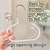 A hand is holding a white, curved hat organizer rack with a large opening design.