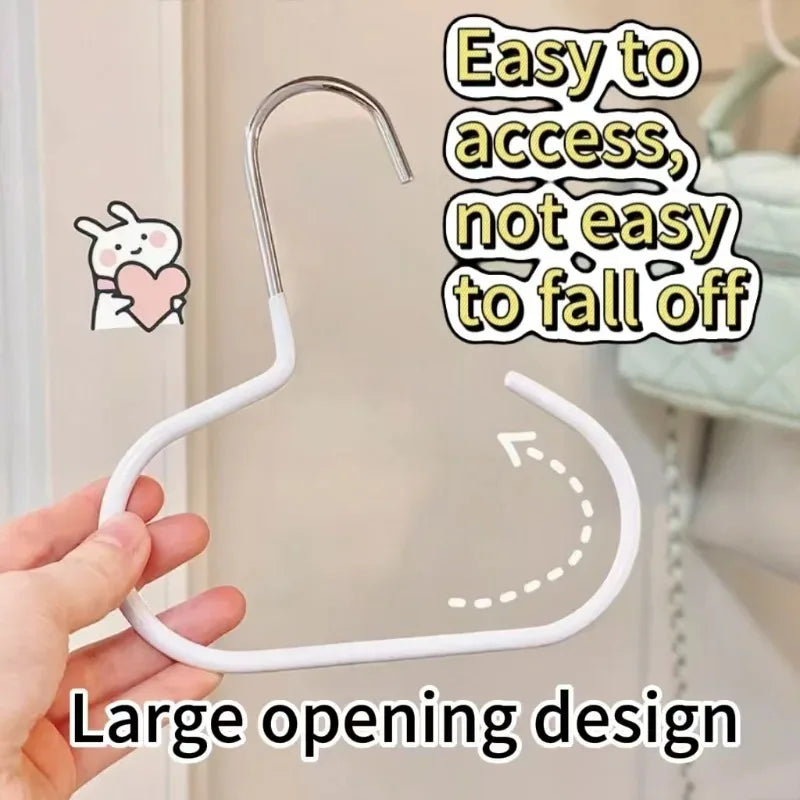 A hand is holding a white, curved hat organizer rack with a large opening design.