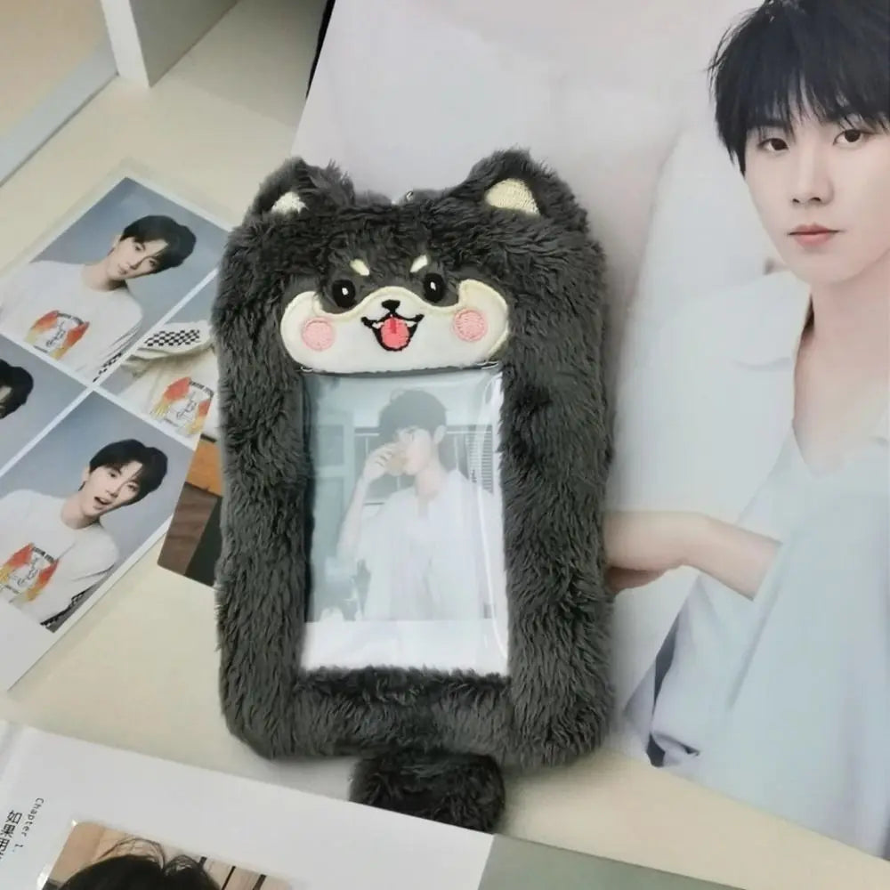 A dark gray plush cat or bear shaped photocard holder with a zipper closure displayed next to a person.