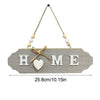 A wooden welcome sign with the word HOME carved into it, featuring a heart cutout and suspended by twine.