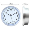 A round silver analog clock with a white face and black hands, shown next to its detached casing.