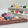A collection of colorful articulated baby dragon figurines displayed on a wooden box.