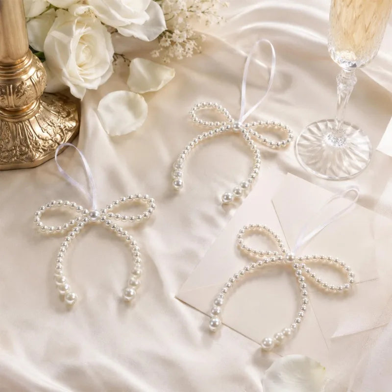 A set of elegant pearl bow ornaments with sheer ribbons displayed on a white satin background.