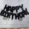 Black foil letter balloons spelling out Happy Birthday strung across a white door