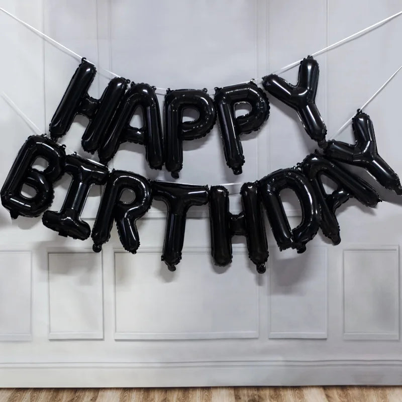 Black foil letter balloons spelling out Happy Birthday strung across a white door