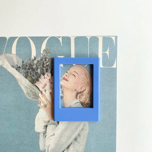 A close-up of a blue magnetic photo frame featuring a woman's face against a muted teal background.