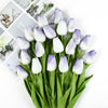A bouquet of artificial white and purple tulips with green stems and leaves.