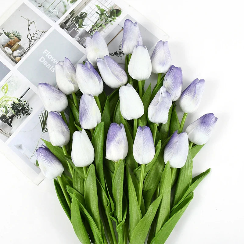 A bouquet of artificial white and purple tulips with green stems and leaves.