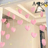 A set of pink heart and star tassel door curtain decorations hanging in a white room.
