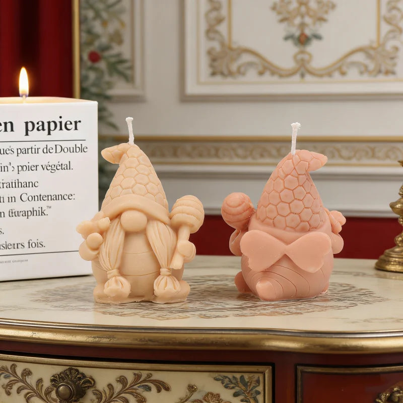 A pink silicone candle mold shaped like a gnome with a honeycomb hat sitting on a decorative table.