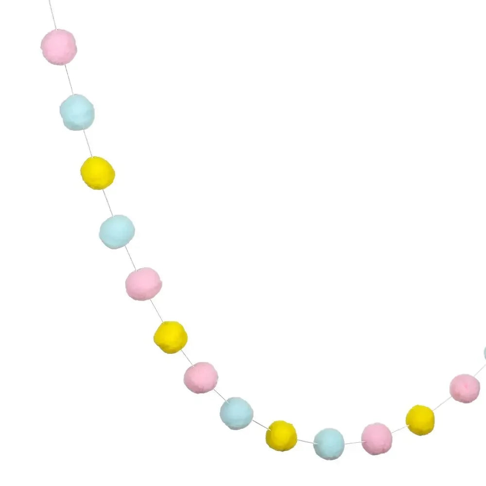 A string of colorful felt balls in pink, light blue, and yellow used for home decor.