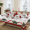 A white Christmas poinsettia rectangle tablecloth set for a dining table with red accents and greenery.