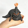 A hand is holding a dark gray 3D printed articulated sea monster fidget toy with an orange finger raised.