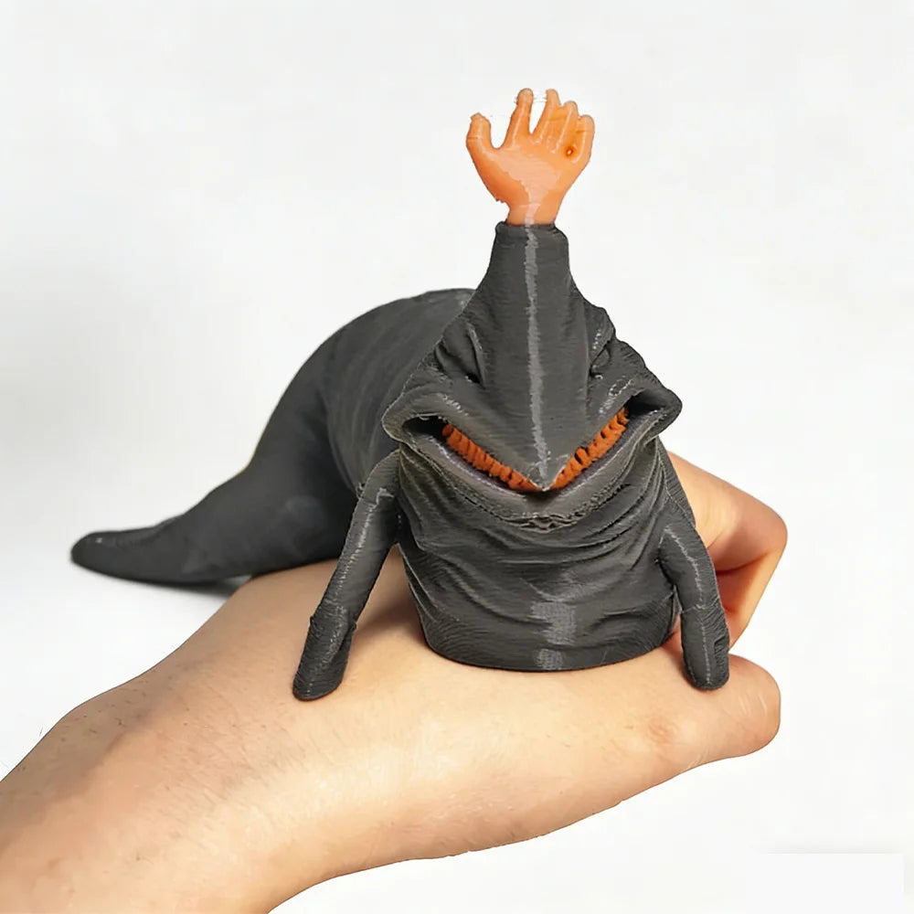 A hand is holding a dark gray 3D printed articulated sea monster fidget toy with an orange finger raised.