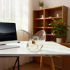 A clear glass vase holding a sprouting avocado seed, displayed on a white desk.