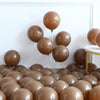 A collection of brown balloons arranged in a display against a white wall.