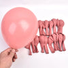 A pink balloon is being held by a hand, next to several pink balloon components.