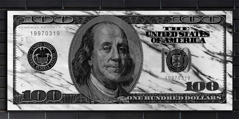 A close-up of a US $100 bill printed on a black brick wall.