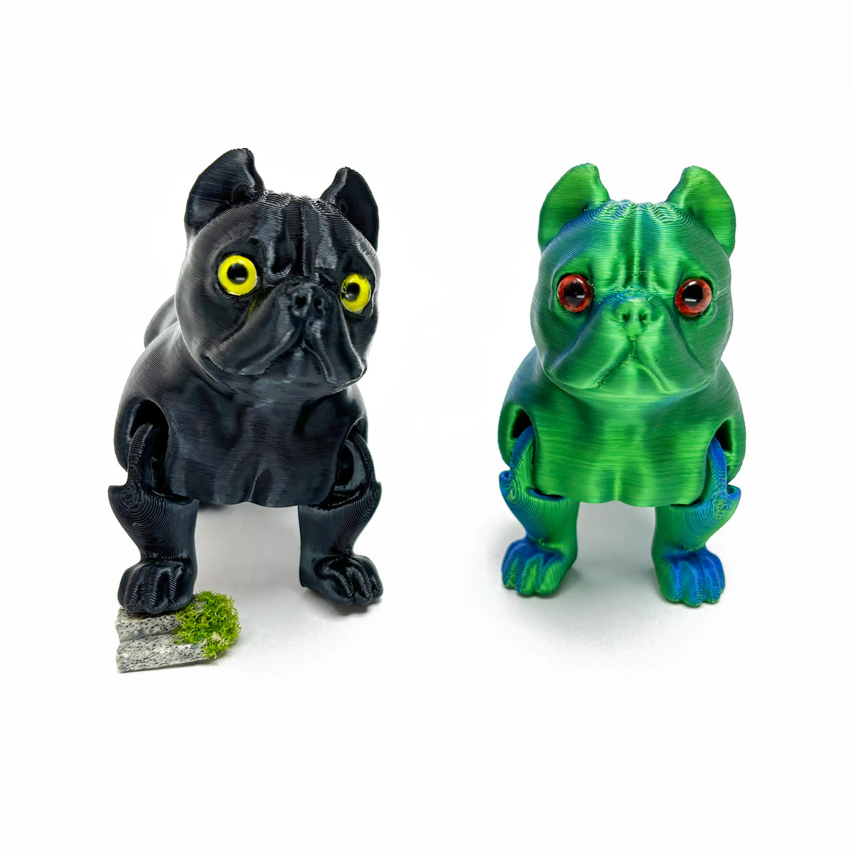 A pair of 3D printed articulated bulldog figurines, one black and one green.
