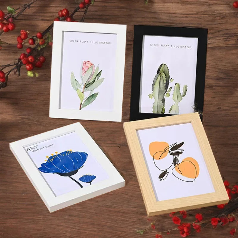 Four framed botanical illustrations in various sizes and colors displayed on a wooden surface.