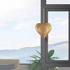 Antique golden metal heart wall decor hanging in a window frame