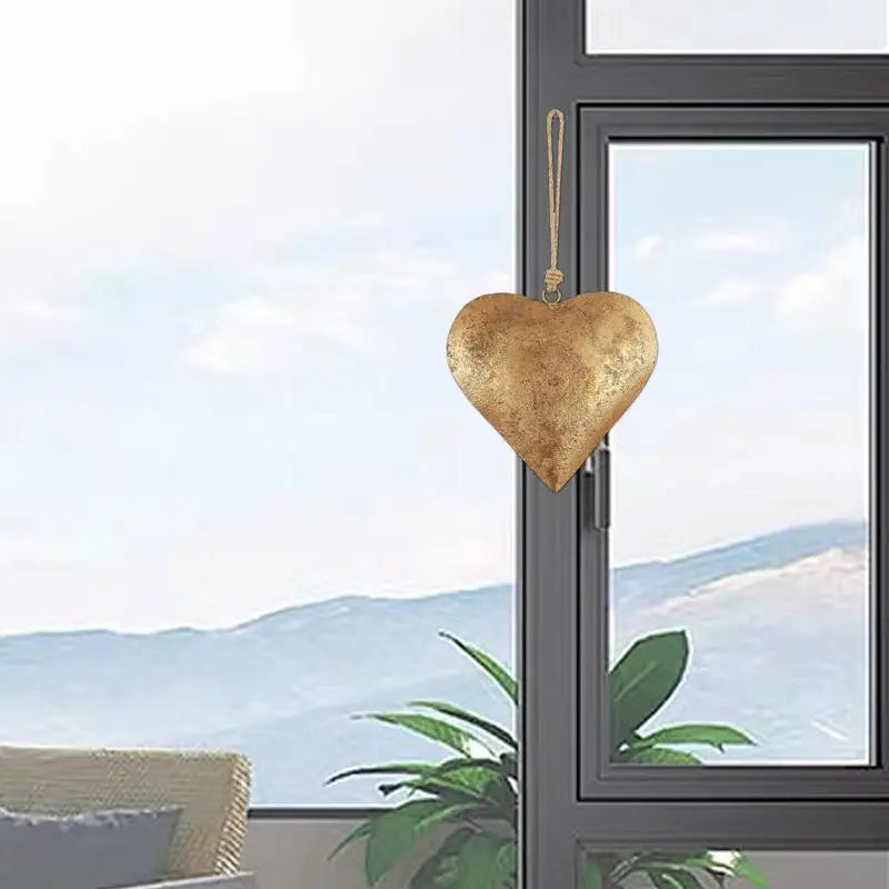 Antique golden metal heart wall decor hanging in a window frame