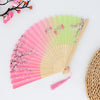 A vintage bamboo folding fan with a rainbow gradient fabric featuring pink and green tones and floral patterns.