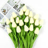 A bouquet of white artificial tulips with green stems and leaves displayed on a white background.