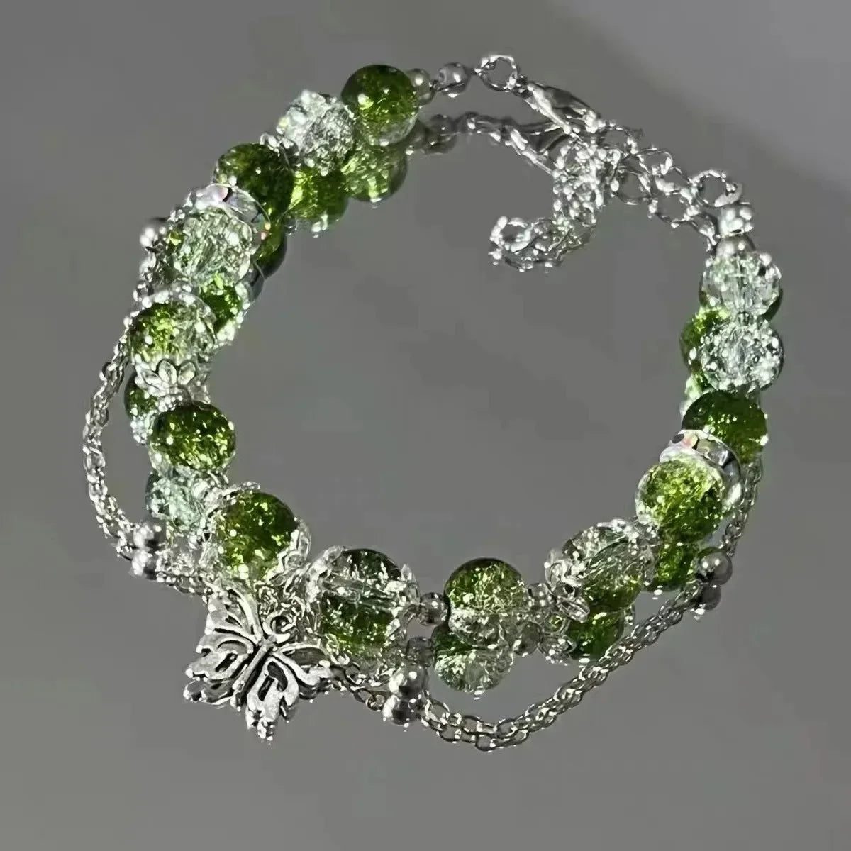 A bracelet made of clear glass beads and green natural stone flowers resembling a lily of the valley.
