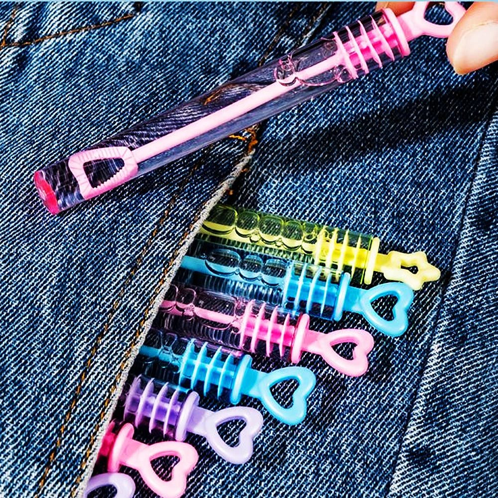 Une main tient un cadeau de fête en bulle rose transparent avec une poignée rose sur un fond en denim.