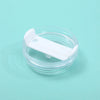 A clear glass jar with a white plastic replacement lid resting on a light blue surface.