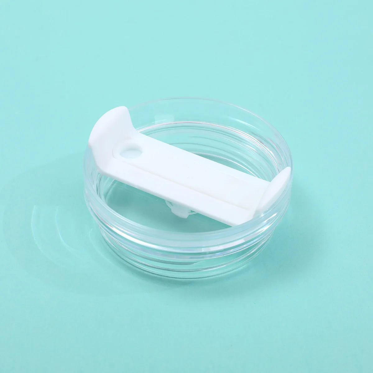 A clear glass jar with a white plastic replacement lid resting on a light blue surface.