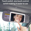 A hand touches a car sun visor vanity mirror with an LED light to switch on the display.